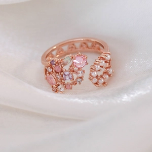 Detail of rose gold adjustable ring with pink crystals, purple stones and small pearls