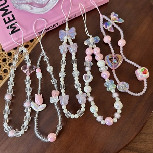 Pink beaded phone charm strap with bow and flower charms on a wooden tray