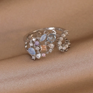 Macro view of silver-tone ring with hollow hearts, colorful zircons and pearl details