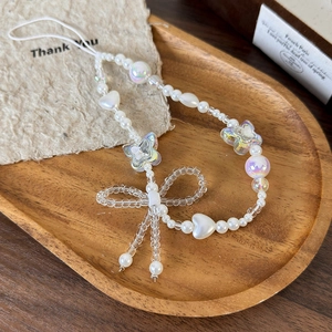 Detail of beaded mobile phone strap with white faux pearls and iridescent bow charms