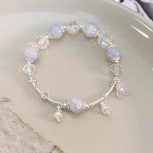 Detailed close-up of fish tail bracelet with lavender beads and pink floral pendant