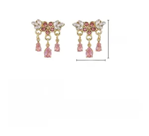 Vue détaillée des boucles d'oreilles fleurs roses avec cristaux et pendentifs gouttes