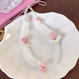 Close-up of pink beaded phone charm with hearts and flowers in a white ceramic bowl