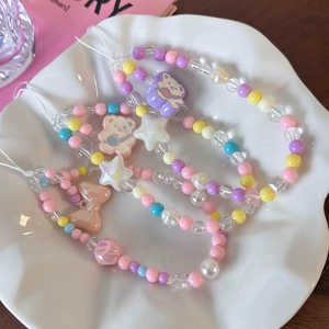 Macro shot of colorful beaded phone straps with cute bear and star charms in a ceramic tray