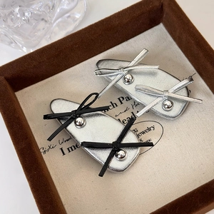 Silver ballet style leather bow hair clips set with metallic beads on velvet display