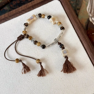 Bracciale etnico con perline, ciondoli a stella e cordino con nappe regolabile