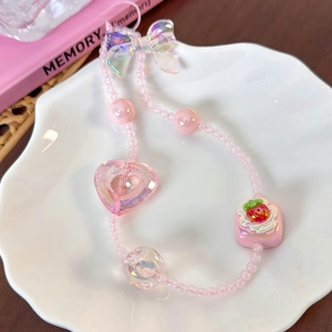 Close-up of pink beaded phone charm with bow, heart and strawberry cake pendants