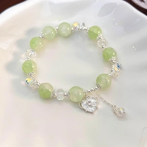 Detail of sweet beaded bracelet with light green beads and silver heart pendant