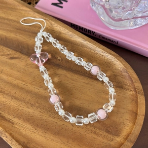 Close-up of pink heart bead phone strap with white pearls on a wooden tray