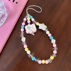 Close-up of colorful bear and star beaded phone strap on a rustic wooden table