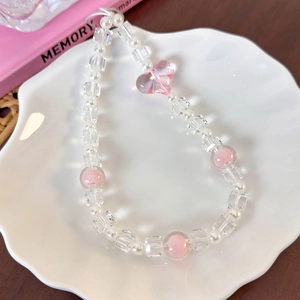Close-up of pink heart bead charm with pearls on a decorative white shell tray