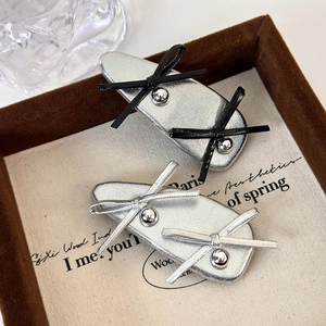 Detail of silver balletcore hair clips with metallic bows and beads on vintage background