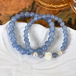 Blaues Kristallarmband mit Kamelienblüte und Perlen in einer dekorativen Schale