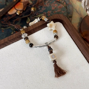 Bracciale etnico con perline in ceramica, pendenti a stella, dettagli retrò e nappe