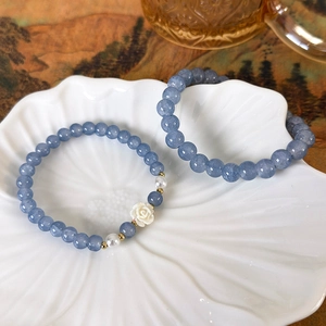 Elegantes Armband mit meerblauen Kristallen und Perlen-Kamelie auf floraler Keramikschale