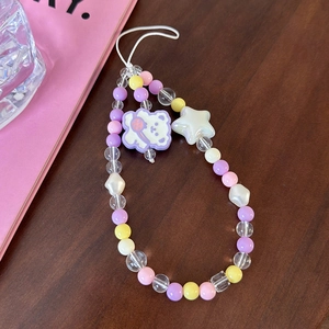 Detail of colorful beaded phone strap with star and purple bear charm on wood