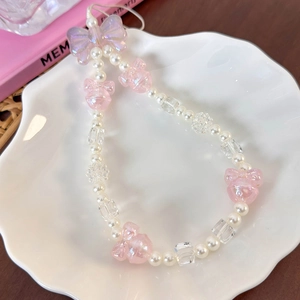Macro shot of pink acrylic bow and pearly beads on the wrist strap in a shell tray