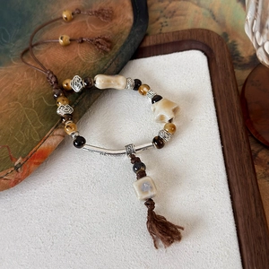 Dettaglio del bracciale etnico con perline a stella, occhio di tigre e cordino regolabile