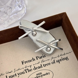 Close-up of silver leather bow hair clip with metal beads on a vintage tray
