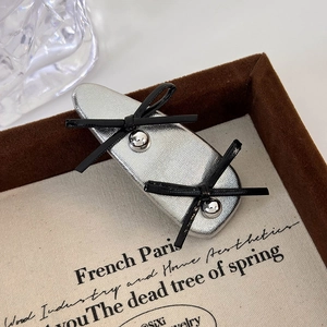 Close-up of silver leather bow hair clip with black ribbons on a vintage velvet tray