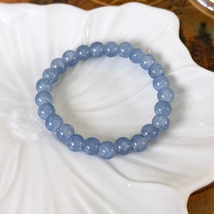 Makroaufnahme von himmelblauen Kristallperlen und Kamelien-Perlenarmband auf Keramikteller