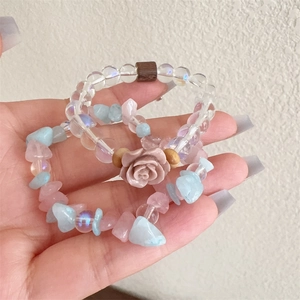 Close-up of beaded bracelets with a pink rose charm and colorful irregular natural stones