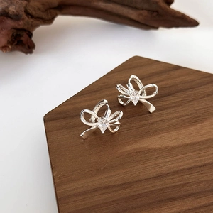 Orecchini a fiocco in argento con zircone a goccia su espositore in legno pregiato