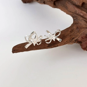 Orecchini a fiocco in argento con zirconi a cuore su un supporto di legno rustico