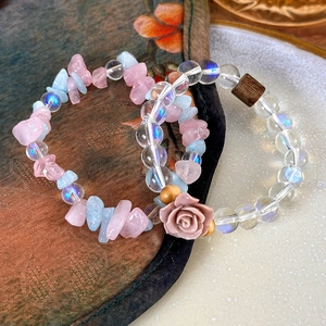 Detailed shot of beaded bracelets with pink roses, colorful stones and clear glass beads
