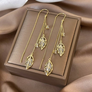 Detail of leaf-shaped cat-eye stone earrings with crystals on a jewelry gift box