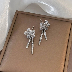 Detail view of silver zircon flower earrings with sparkling pendant on leather background