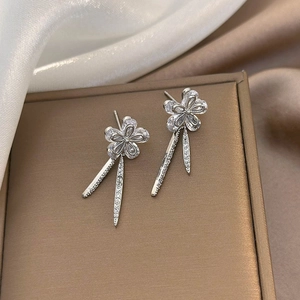 Detailed view of silver flower tassel earrings with shimmering zircon stones on silk