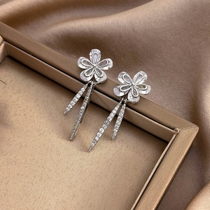 Close-up of elegant silver flower drop earrings with sparkling zircon tassels on silk fabric