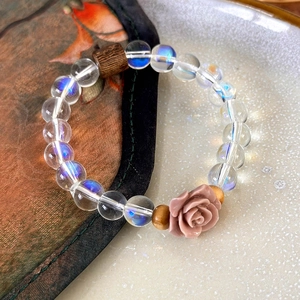 Detailed close-up of crystal aurora beads with a pink resin rose and wooden spacer