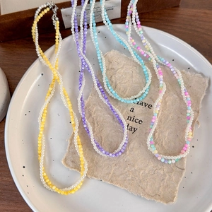 Macro shot of colorful beaded pearl necklaces in a ceramic plate with vintage paper