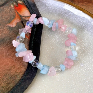 Detail view of the rose quartz beaded bracelet on a vintage floral cloth and ceramic plate