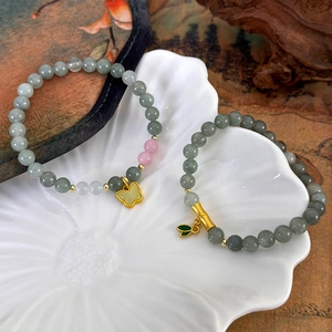 Bracelets en perles de jade avec pendentifs papillon et bambou dans un plateau en céramique