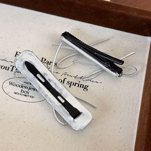 Detail view of silver and black metal hair clips displayed on a vintage fabric jewelry box