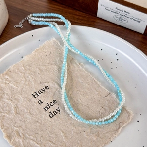 Detail view of double-layered beaded necklace with light blue and white pearls and silver clasp
