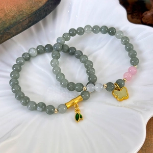 Bracelets en perles de jade avec pendentifs bambou et papillon en or sur assiette