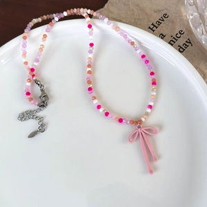 Detail van kleurrijke glazen kralenketting met roze strikhanger en zilveren sluiting