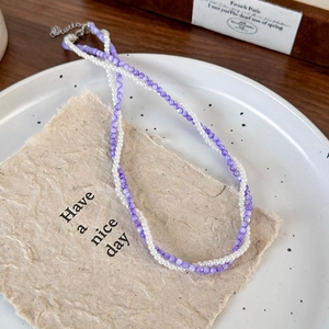 Close-up of double-layer purple and white beaded necklace with silver lobster clasp detail