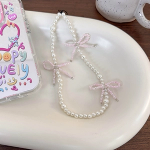 Detail view of handmade pink beaded bows and white imitation pearls on a mobile phone strap