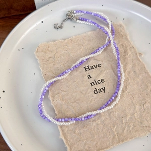 Detail of double-layer beaded necklace with purple beads and white imitation pearls