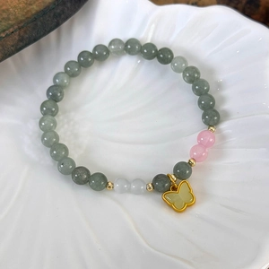 Gros plan de perles de jade naturel avec pendentif papillon doré dans un plat coquille