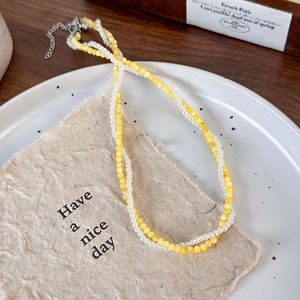 Detail of double-layer beaded necklace featuring yellow translucent beads and small pearls