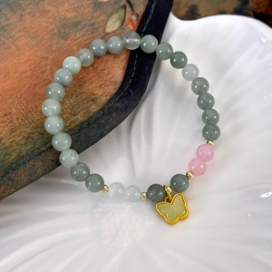 Détail du bracelet en perles de jade avec pendentif papillon doré élégant