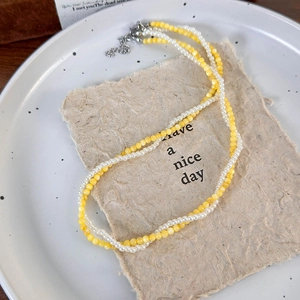 Close-up of double-layered beaded necklace with yellow beads and white pearls