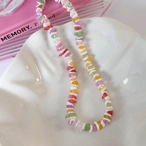 Détail de perles en gravier coloré et entretoises en coquillage blanc sur un collier d'été