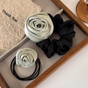 Detailed view of handmade satin rose hair scrunchies in sage green with elastic bands